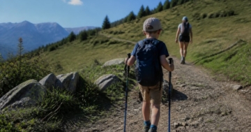 Kind mit kurzen Trekkingstöcken auf dem Wanderweg