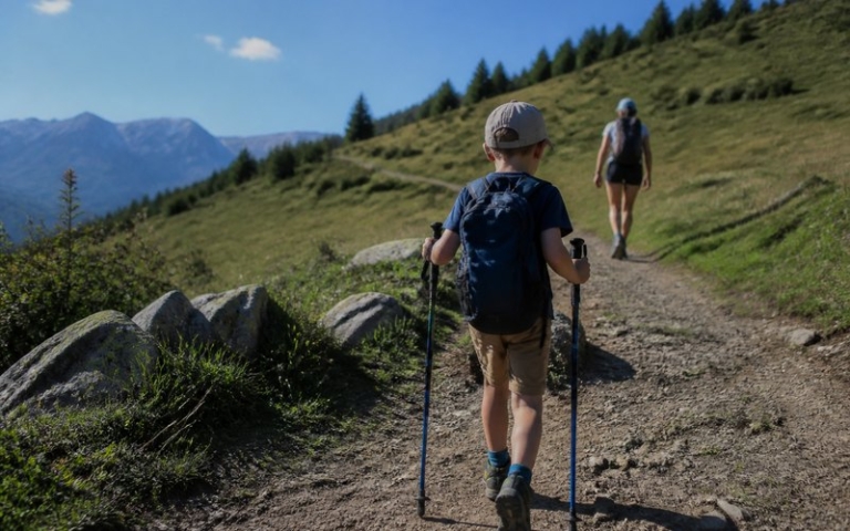 Kind mit kurzen Trekkingstöcken auf dem Wanderweg
